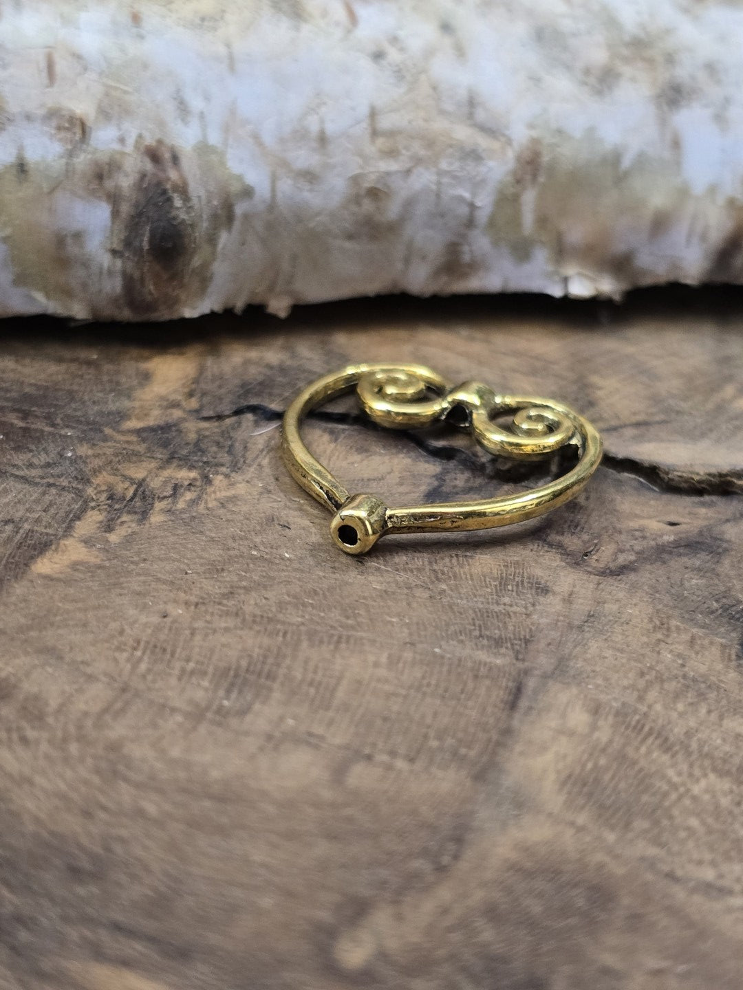 Detailansicht der unteren Bohrung eines herzförmigen Perlenrahmens in Gold zur Veranschaulichung des Fädelkanals.