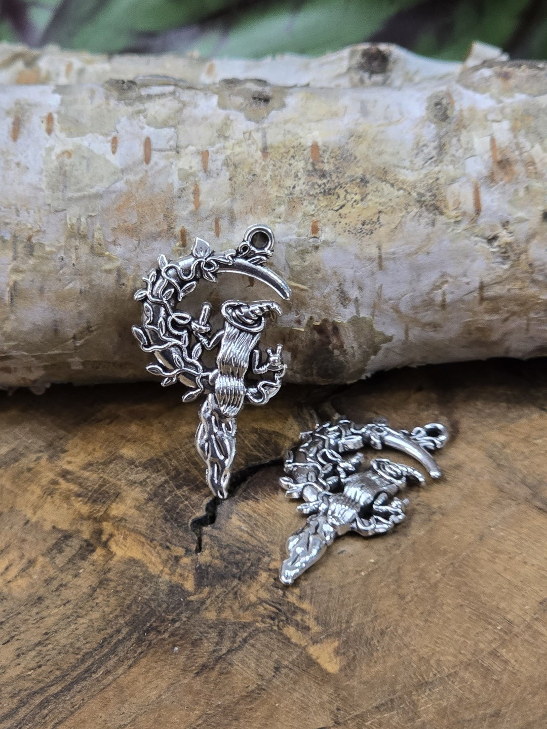 Detailansicht von zwei Hexen-Mond-Charm-Anhängern aus Metall auf Holzplatte