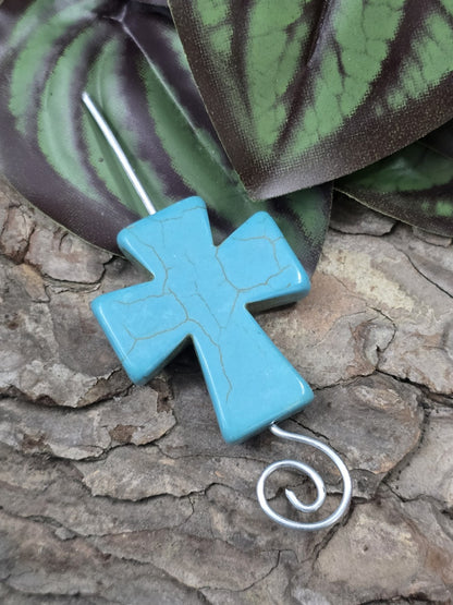 Howlith Kreuzperle in Türkis mit durchgefädeltem Ösendraht aus Silber auf Baumrinde drapiert
