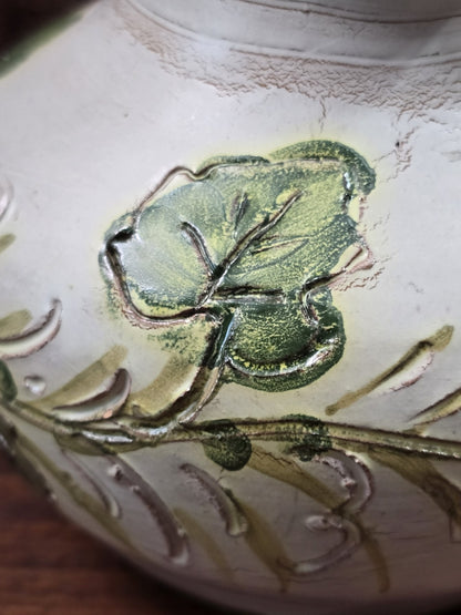 Vintage Keramikkrug mit grünem Efeublatt, reliefartigen Konturen und feiner Oberflächenstruktur in enger Detailaufnahme