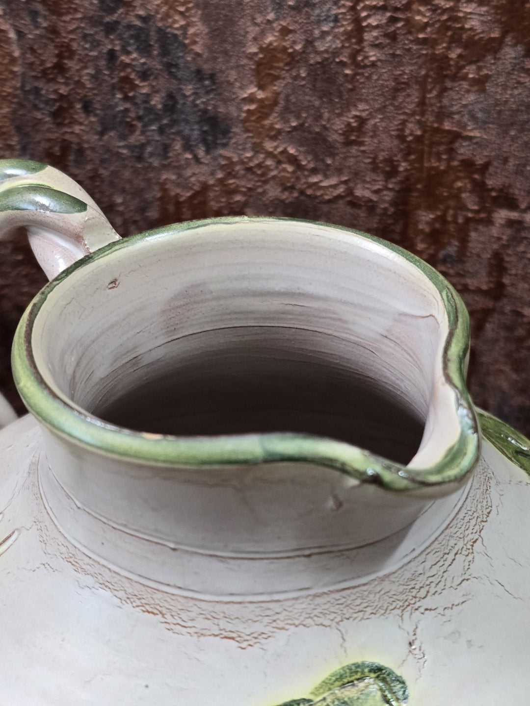 Vintage Keramikkrug mit geschwungenem Ausguss, grün eingefasstem Rand und sichtbarer Innenfläche aus heller Keramik von oben
