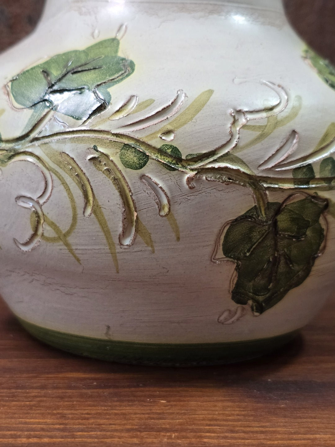 Vintage Keramikkrug mit grünem Efeurelief, geschwungenen Ranken und cremefarbener Oberfläche in dekorativer Detailaufnahme
