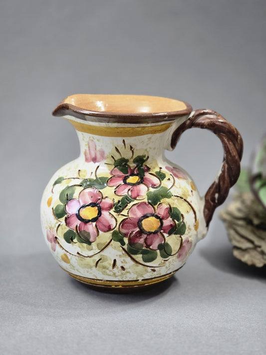 Bauchiger Vintage Keramik Krug mit rosa Blumen, grünem Blattdekor, braunem Henkel und Ausguss auf grauem Hintergrund