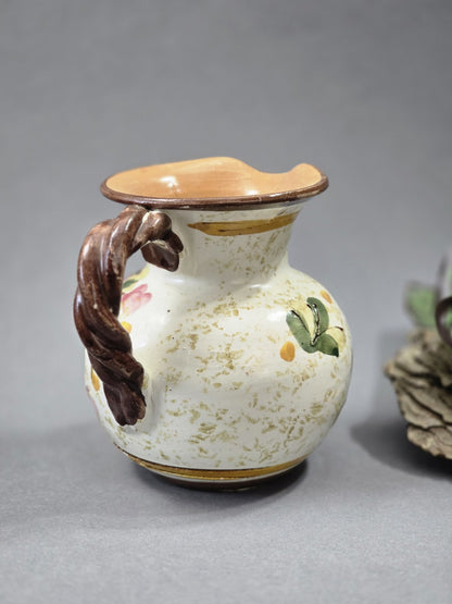 Rückseite des Vintage Blumenkrugs mit hellem Keramikkörper, braunem Henkel, gesprenkelter Oberfläche und gewelltem Ausguss
