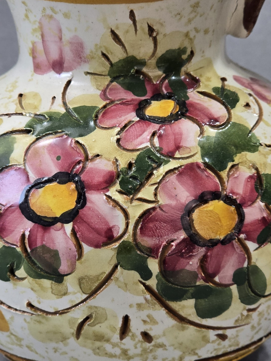 Nahaufnahme der rosa Blüten und grünen Blätter auf dem Vintage Keramik Krug mit fühlbaren Ritzlinien und glänzender Glasur