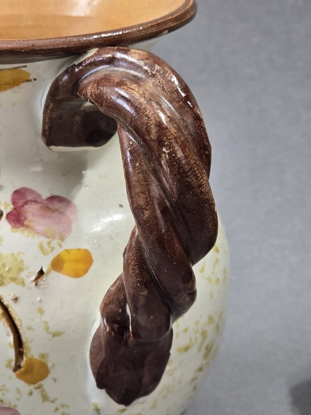 Detail des braunen gedrehten Henkels an einem floralen Vintage Keramik Krug mit sichtbarer Struktur und handwerklicher Optik