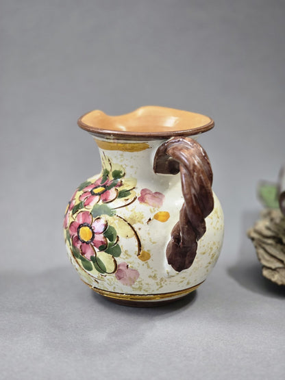 Seitliche Produktansicht eines handbemalten Keramik Krugs mit Blumenmuster, braunem gedrehtem Henkel und warmem Innenrand