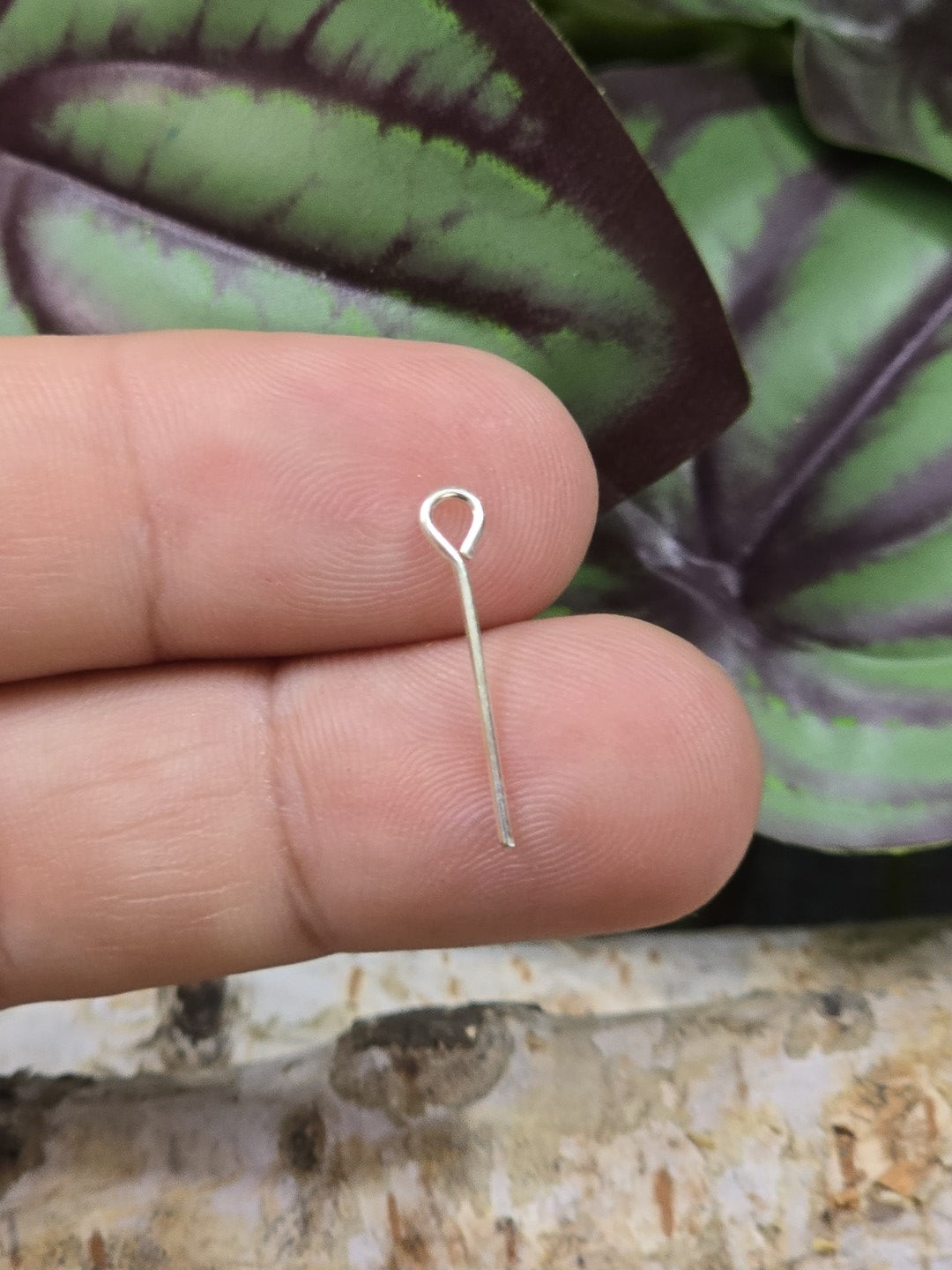Einzelner versilberter Kettelstift 18 mm als Größenvergleich auf der Fingerspitze gehalten