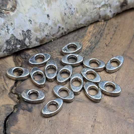 16 schöne ovale Metallperlen in Antiksilber, Augenform, 10mm. Die Perlen haben einen runden Ausschnitt in der Mitte und ein längs verlaufendes Fädelloch. Sie eignen sich hervorragend als Abstandhalter oder für dezente Akzente in Armbändern, Ketten und Ohrschmuck. Menge: 16 Stück.