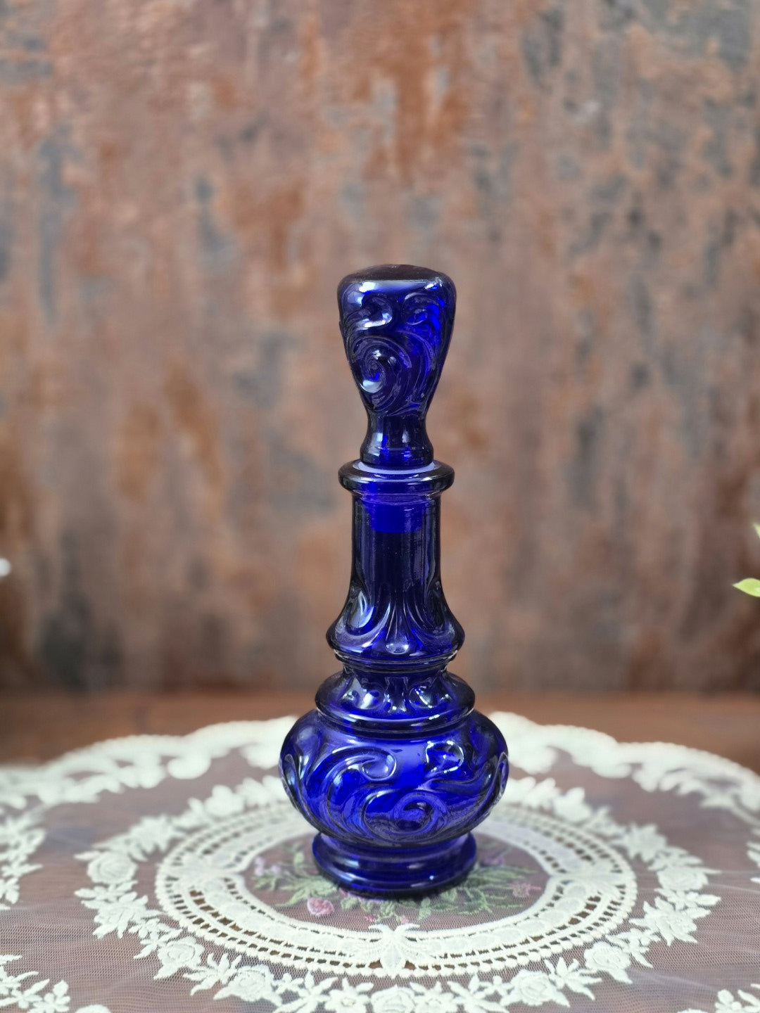Vintage Glasflakon aus tiefblauem Glas mit bauchigem Korpus, geschwungenem Relief und ornamental gestaltetem Stopfen in Gesamtansicht