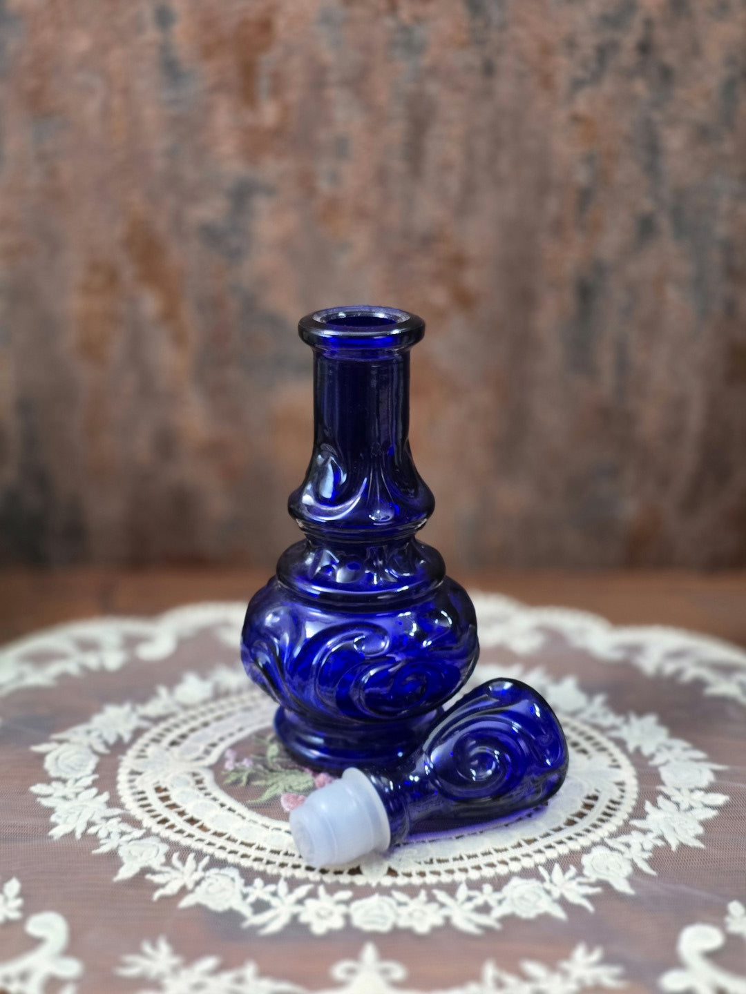 Vintage Glasflakon aus blauem Reliefglas mit abgenommenem Stopfen und sichtbarer Flaschenöffnung in leicht gedrehter Produktansicht