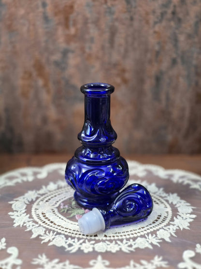 Vintage Glasflakon aus blauem Reliefglas mit abgenommenem Stopfen und sichtbarer Flaschenöffnung in leicht gedrehter Produktansicht