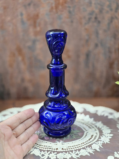 Vintage Glasflakon in kräftigem Kobaltblau mit Reliefdekor und Glasstopfen neben einer Hand als Größenvergleich