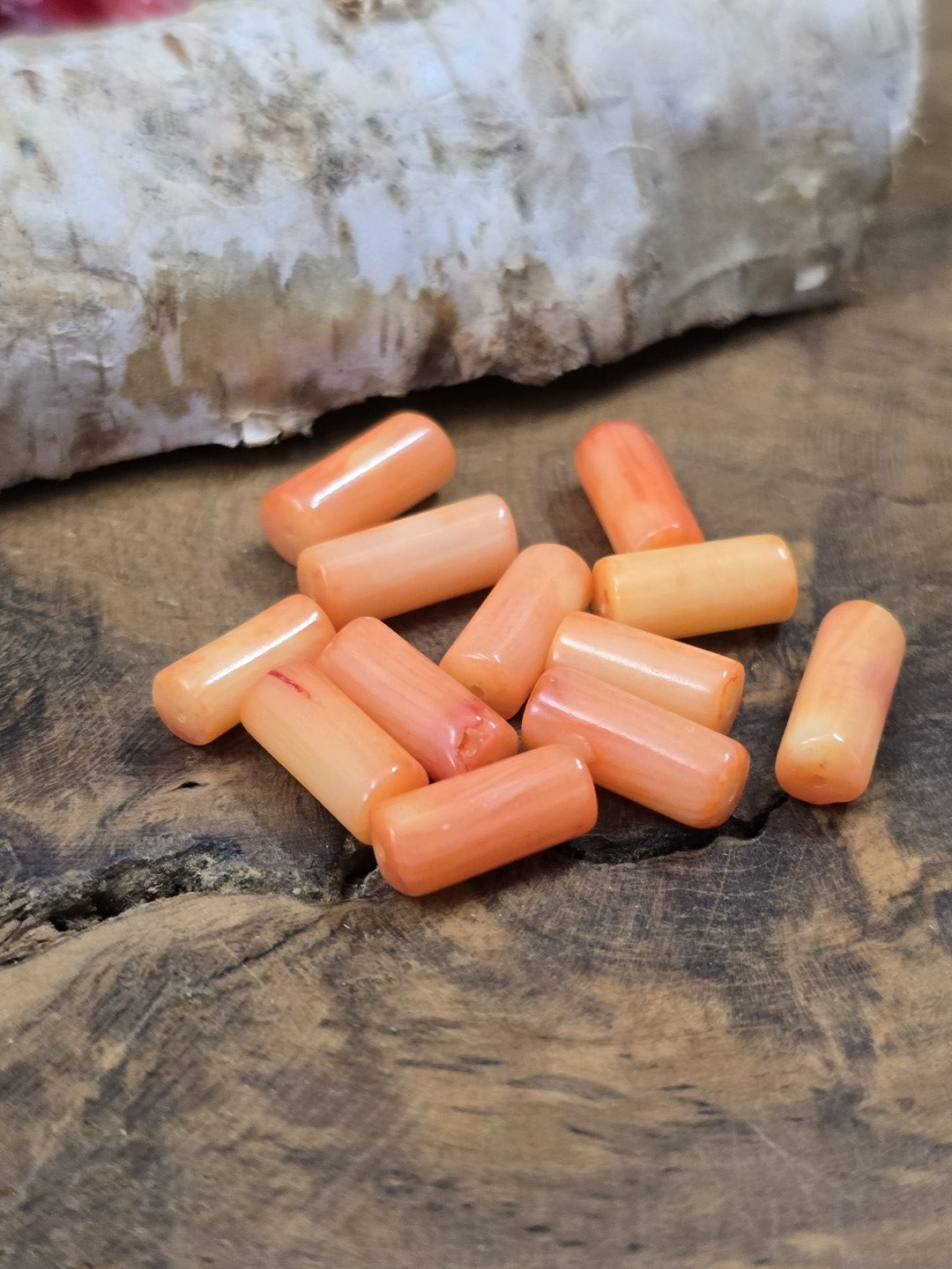 Draufsicht auf eine Gruppe zylindrischer Schaumkorallen-Perlen in natürlichen Lachs- und Orangetönen.