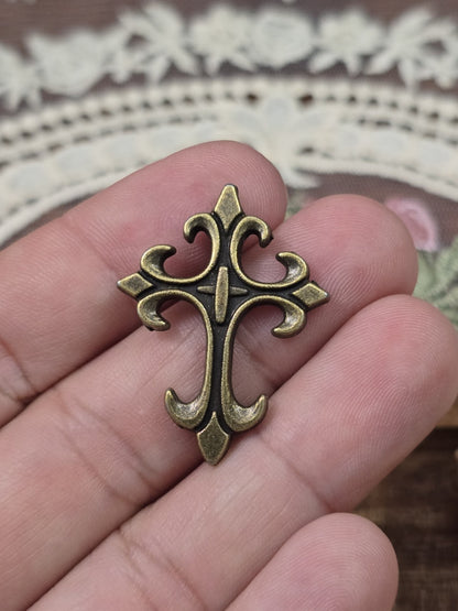Barockes Kreuz 32x24mm in Bronze-Optik schräg auf Hand gehalten als Größenvergleich.