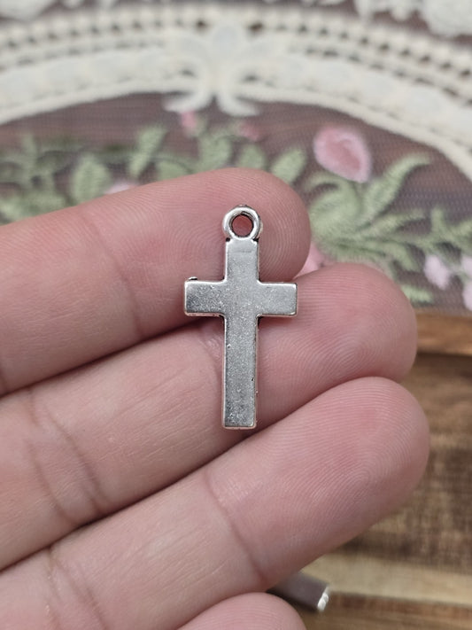 Schlichtes Kreuz 25x13mm in Silber-Optik quer auf Fingern gehalten als Größenvergleich.