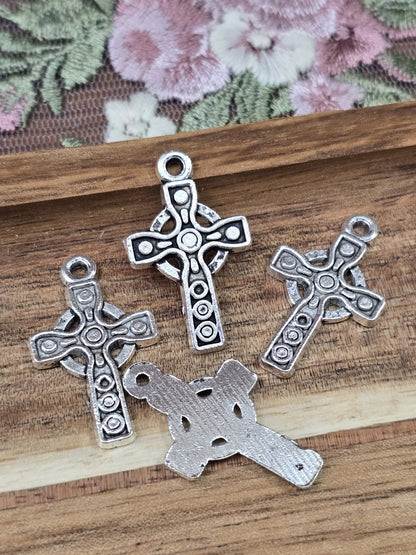 Vier keltische Kreuz-Anhänger in Antiksilber von Vorder- und Rückseite auf Holzgrund.