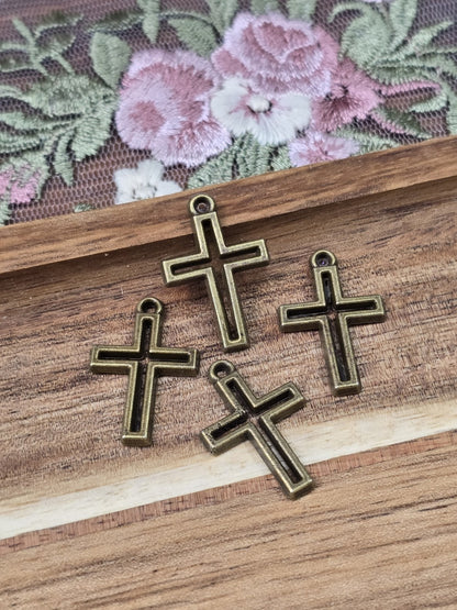 Detailaufnahme von vier schlichten Kreuz-Metallanhängern mit Öse für Schmuckherstellung.