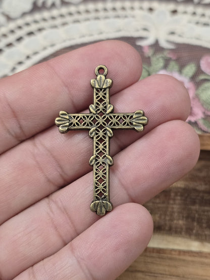 Gothic-Kreuz-Charm 41x25mm in Bronze-Optik auf der Hand gehalten als Größenvergleich.