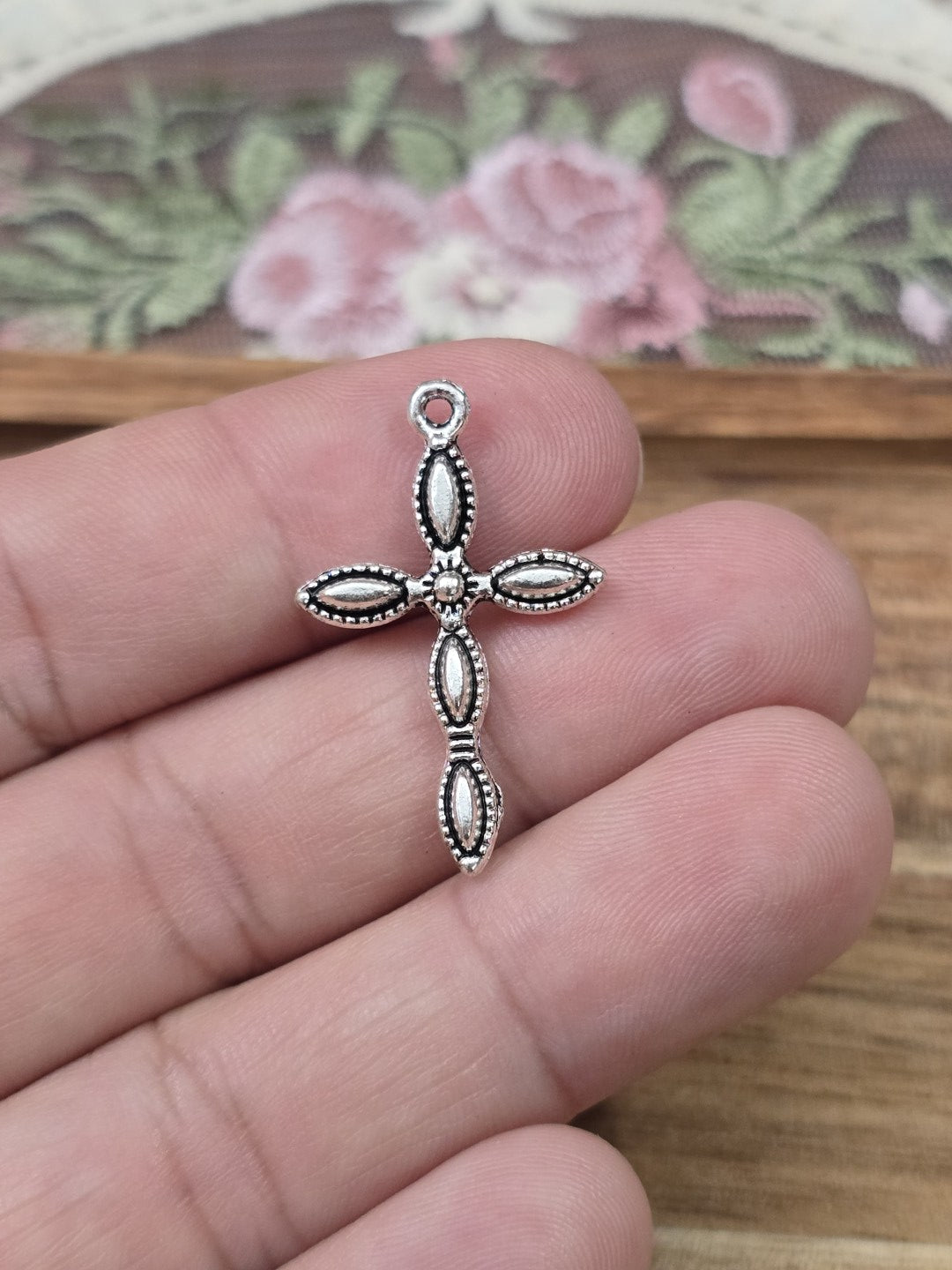 Filigraner Metall-Kreuzanhänger 29x18mm in Silber auf Hand gehalten als Größenvergleich.