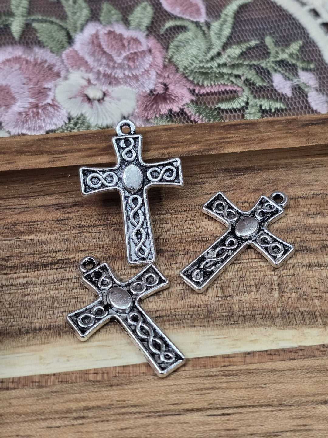 Detailaufnahme von drei antiken Kreuz-Metallanhängern mit Ornament-Muster für Schmuckherstellung.