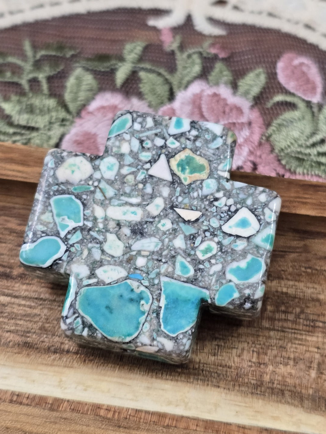 Draufsicht der flachen Stein-Kreuzperle mit türkis-grüner und weißer Mosaik-Maserung.