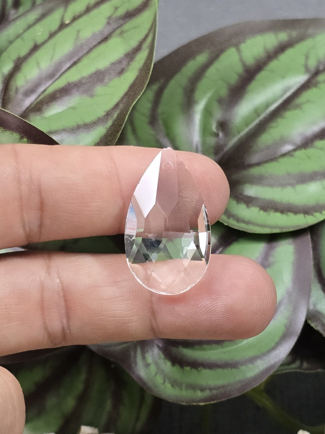 28 mm Kristallglas-Tropfen in transparenter Optik auf Fingern als Größenvergleich
