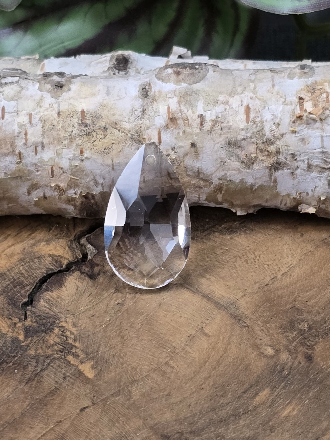 Farbloser Glas-Tropfenanhänger frontal fotografiert mit Lichtreflexen auf den Facetten
