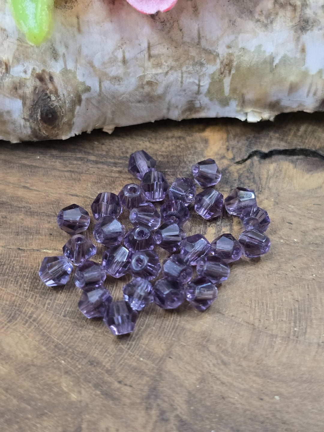 Nahaufnahme von facettenreichen Kristallglas-Bicones (4 mm) in Amethyst-Lila für die Schmuckherstellung.
