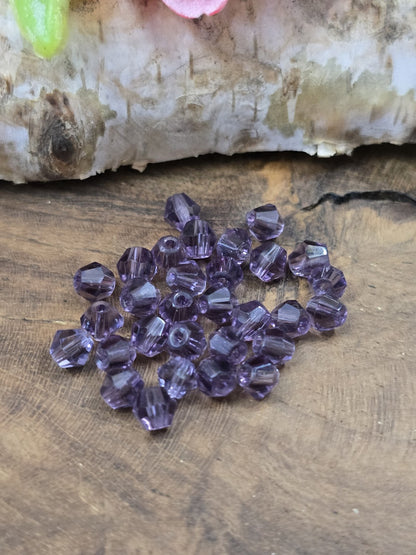 Nahaufnahme von facettenreichen Kristallglas-Bicones (4 mm) in Amethyst-Lila für die Schmuckherstellung.