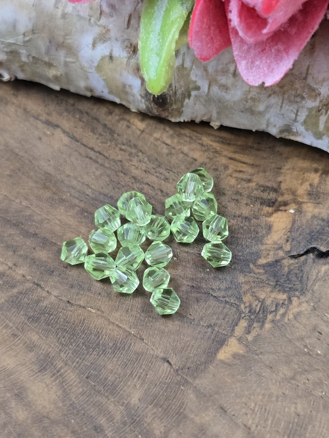 Nahaufnahme von geschliffenen Kristallglas-Bicones (4 mm) in Peridot-Grün für die Schmuckherstellung.