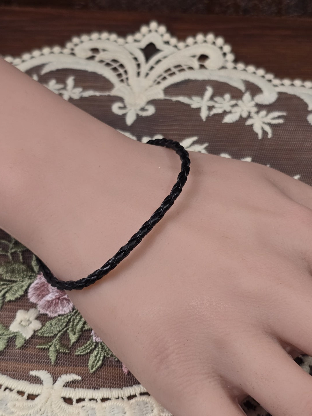 Geflochtenes Kunstleder-Armband in Schwarz getragen am Handgelenk.