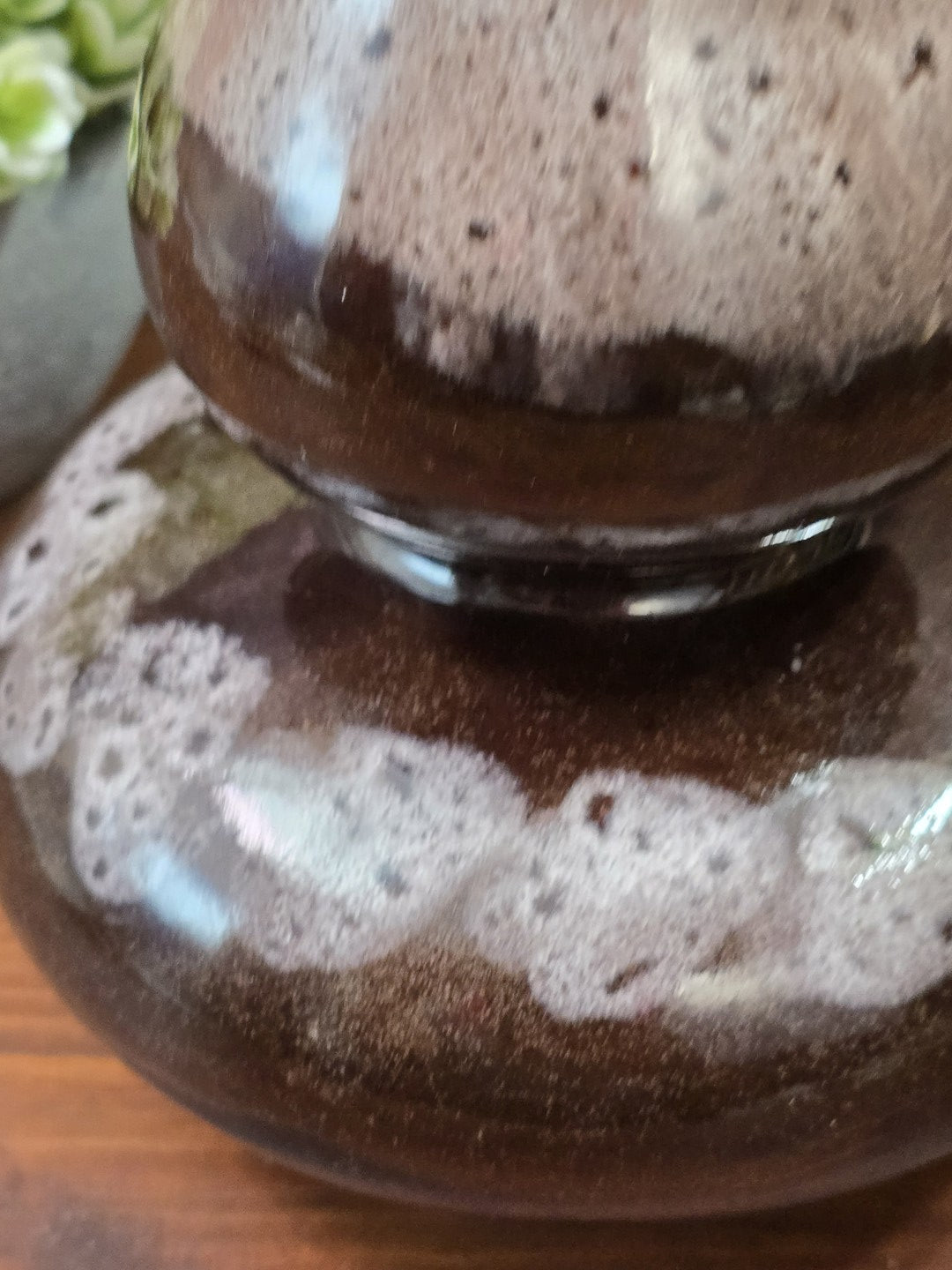 Vintage Keramikvase mit glänzender brauner Glasur und fein gesprenkeltem beige-grauem Verlauf am oberen Gefäßteil in Nahaufnahme.
