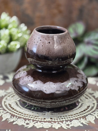 Vintage Keramikvase mit dunkler Glanzglasur, beige gesprenkeltem Halsbereich und hellem Dekorband auf einer Spitzendecke.