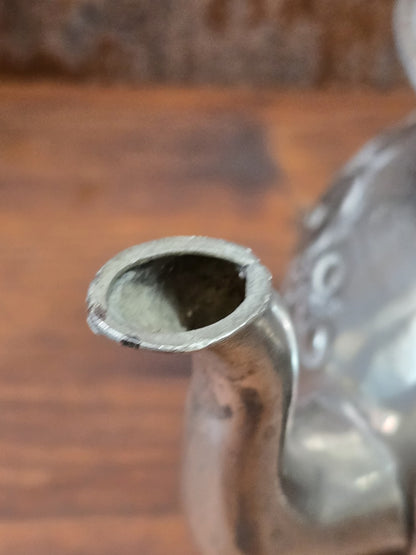 Versilberte Teekanne mit Nahaufnahme des schmalen Ausgusses, sichtbarer Öffnung, Patina und weichem Hintergrund
