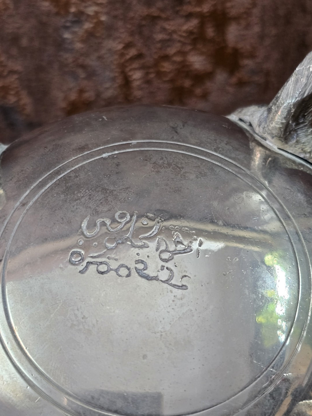 Versilberte Teekanne mit Nahaufnahme der Signatur auf dem Boden, sichtbarer Patina und reflektierender Oberfläche
