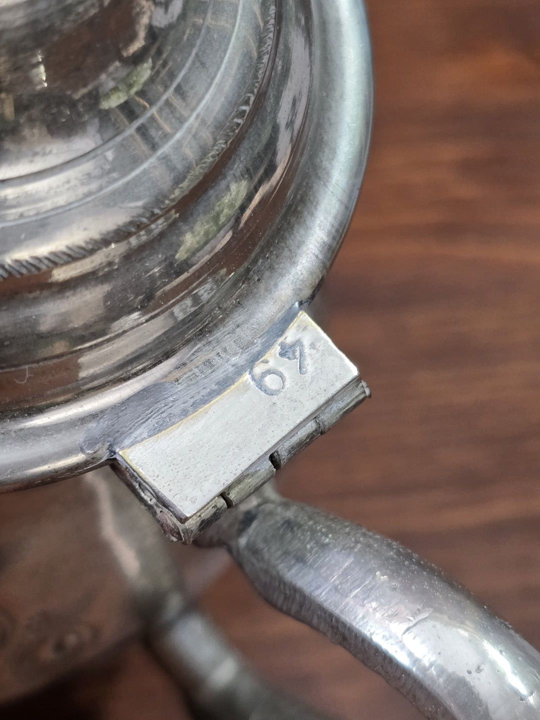 Versilberte Teekanne mit Nahaufnahme der Scharnierplatte, eingravierter Zahl 67 und matter Patina am Deckelrand