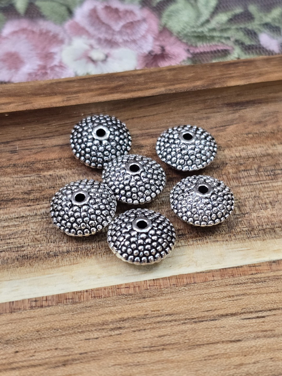 Flach-runde Zwischenperlen in Altsilber-Optik mit Perlstruktur für DIY-Schmuckprojekte.