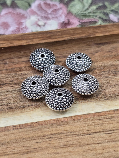 Flach-runde Zwischenperlen in Altsilber-Optik mit Perlstruktur für DIY-Schmuckprojekte.