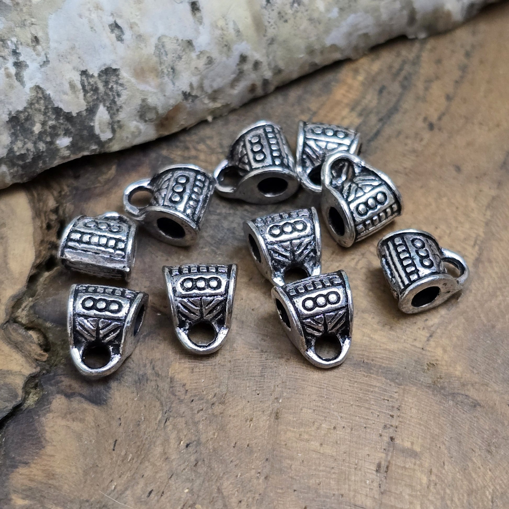 10 Metallperlen mit Öse, antiksilberfarben, 7 x 9 mm. Jede Perle ist mit einem feinen Ethnomuster verziert. Das große Fädelloch (ca. 3 mm) ermöglicht einfaches Auffädeln. Mit der Öse können Anhänger befestigt werden. Perfekt für Armbänder, Ketten und kreative Designs.