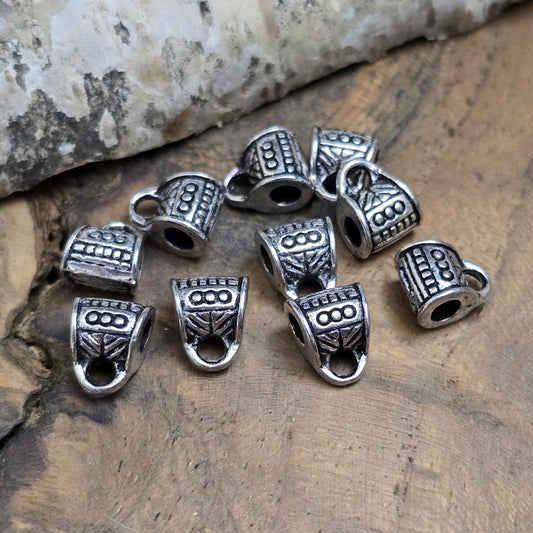 10 Metallperlen mit Öse, antiksilberfarben, 7 x 9 mm. Jede Perle ist mit einem feinen Ethnomuster verziert. Das große Fädelloch (ca. 3 mm) ermöglicht einfaches Auffädeln. Mit der Öse können Anhänger befestigt werden. Perfekt für Armbänder, Ketten und kreative Designs.