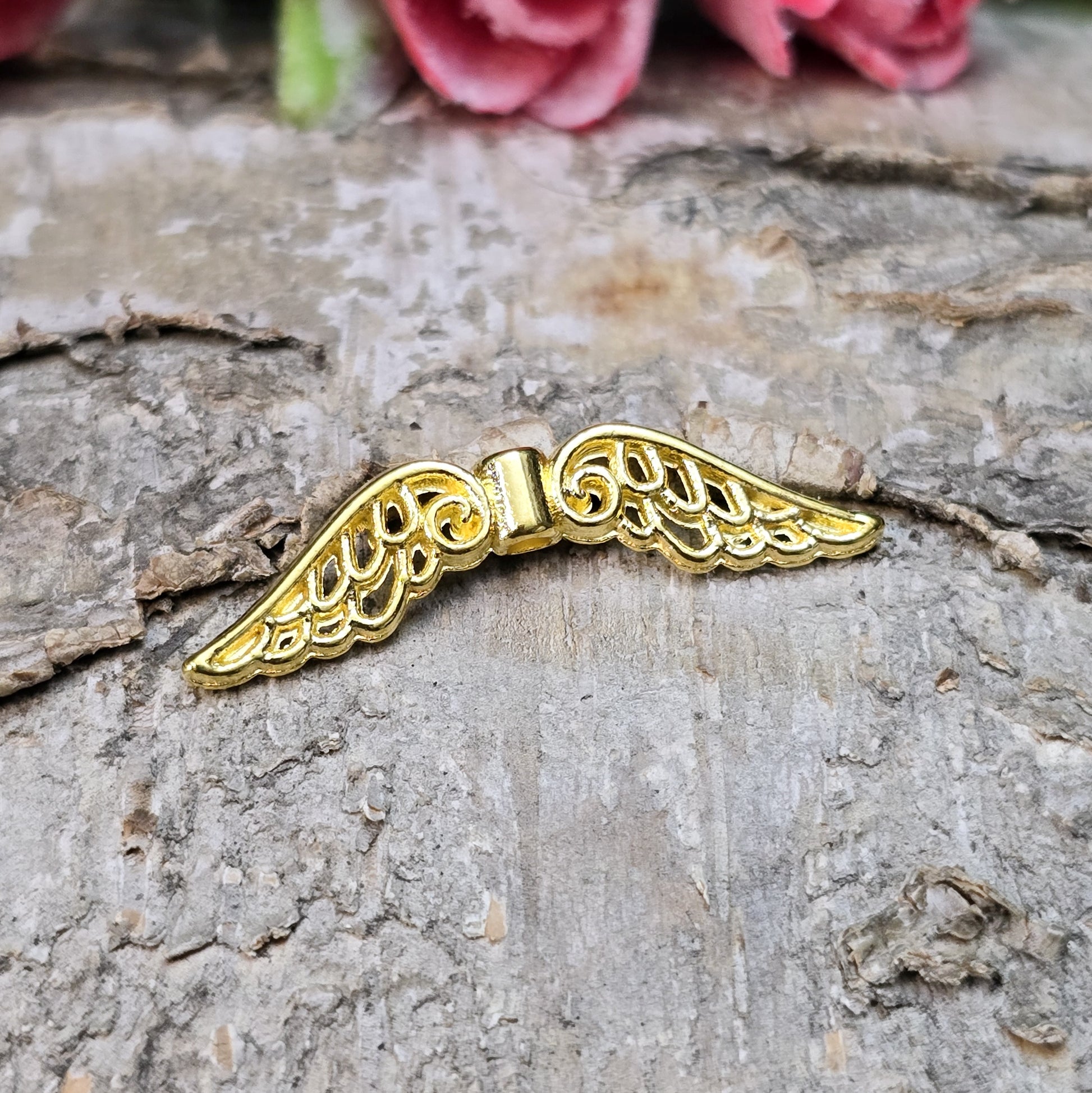 Das Bild zeigt mehrere vergoldete Flügelperlen aus Metall, jeweils 30 mm breit. Die Flügel sind filigran gestaltet, mit geschwungenen Linien und feinen Details. Sie eignen sich ideal zur Herstellung von Schutzengeln für Schmuck, Schlüsselanhänger oder Dekorationen. Die glänzende Goldfarbe verleiht ihnen eine edle und elegante Optik.