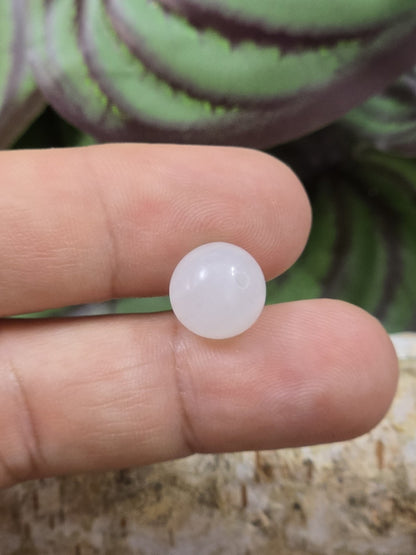Weiße Milchquarz-Perle mit 10 mm Durchmesser auf den Fingern als Größenvergleich