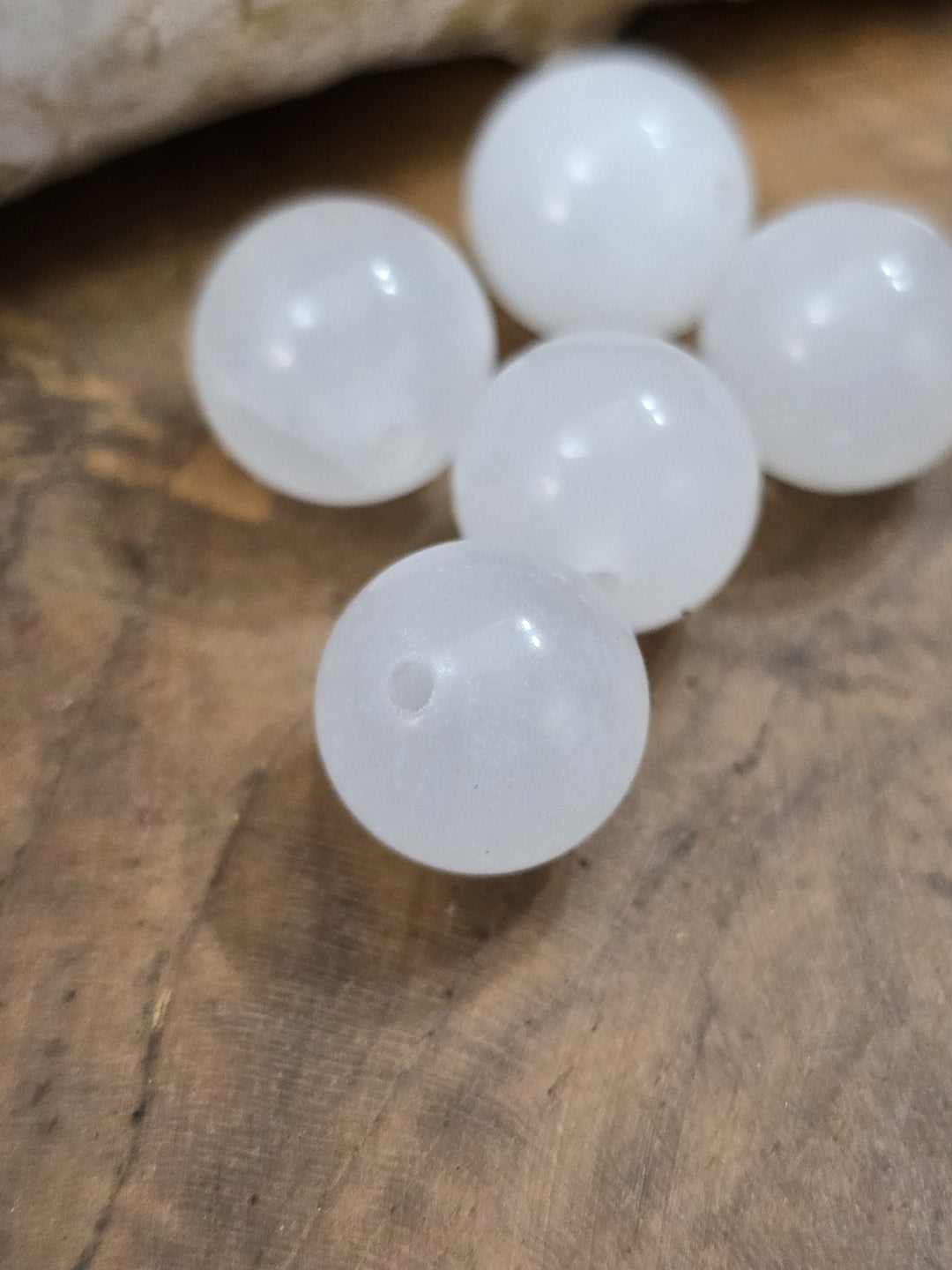 Detailansicht einer weißen Milchquarz-Perle mit sichtbarer Bohrung und glänzender Oberfläche