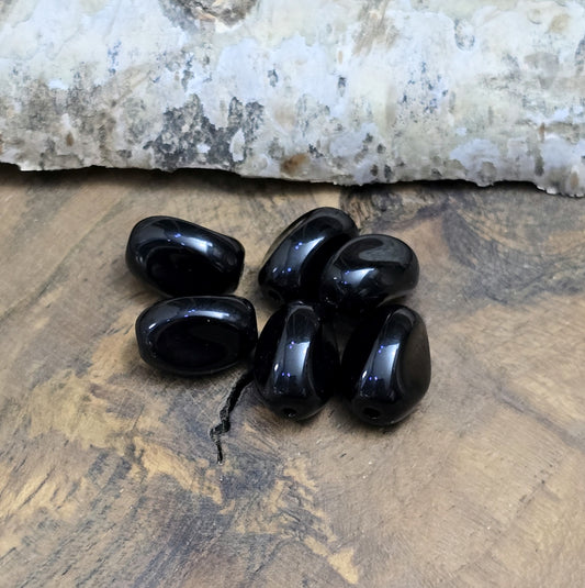 Das Bild zeigt 12 opak schwarze Glasperlen in Nuggetform – 13mm – Für deinen eleganten Schmuck
