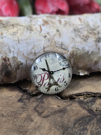 Nahaufnahme eines einzelnen 16 mm Cabochons aus Glas mit französischem Poststempel, Eiffelturm und Uhr-Motiv zum Basteln von Ketten und Ohrringen.