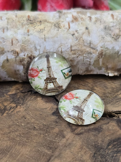 Zwei Paris-Schmucksteine aus Glas mit nostalgischem Eiffelturm- und Rosen-Motiv dekorativ arrangiert auf Holz vor einem Birkenast.