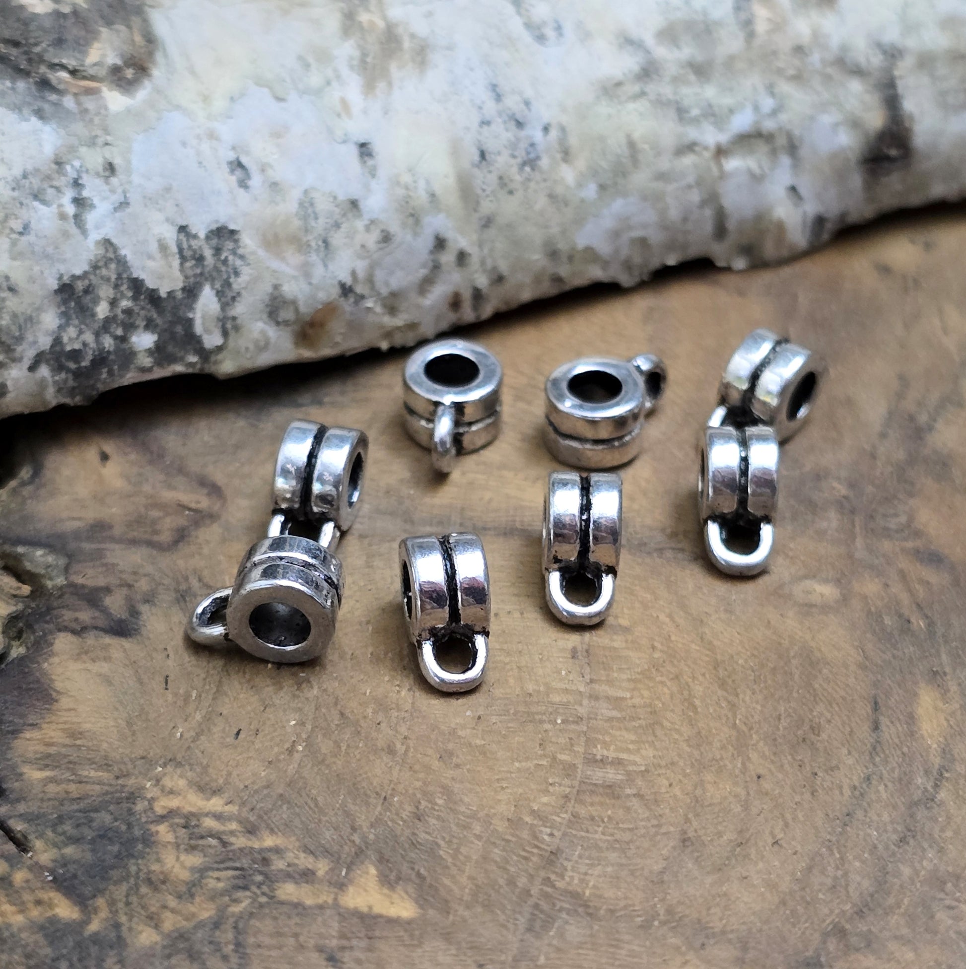 Das Bild zeigt antiksilberfarbene Metallperlen mit Öse. Sie sind eine ideale Ergänzung für kreative Schmuckprojekte. Dank des großzügigen 3-mm-Lochs lassen sie sich mühelos auf verschiedene Bänder und Kordeln auffädeln. Die zusätzliche Öse eröffnet zahlreiche Designmöglichkeiten, um Schmuckstücke individuell zu gestalten.