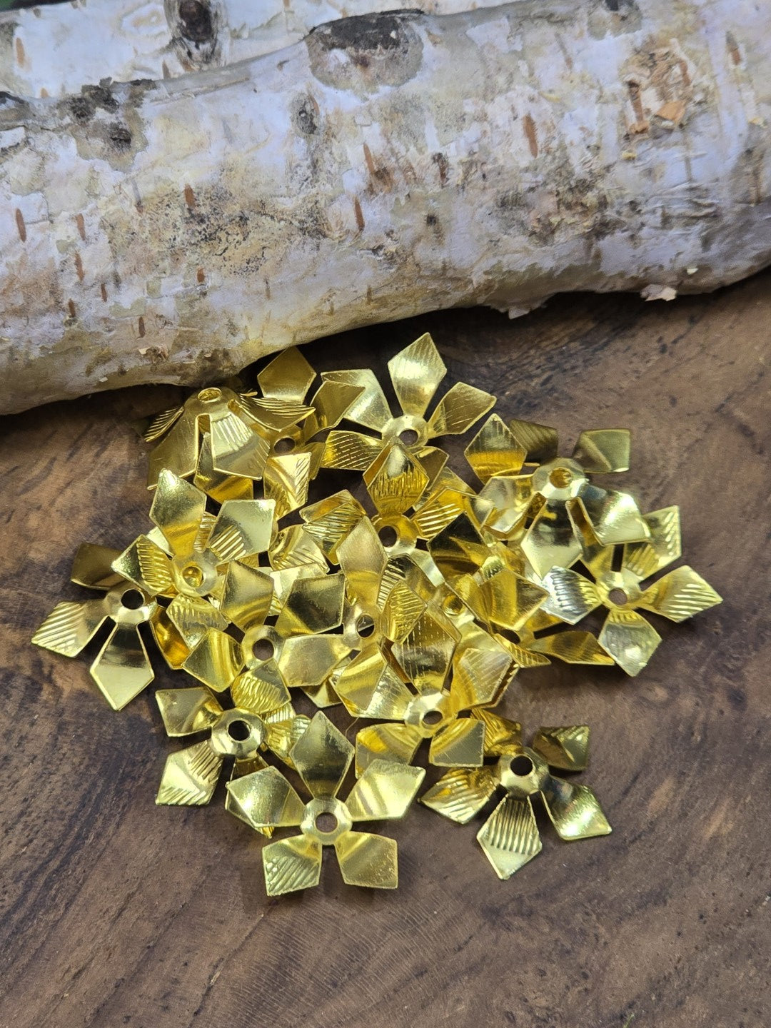 Draufsicht auf blütenförmige goldene Zwischenperlen und Perlenkappen 16 mm