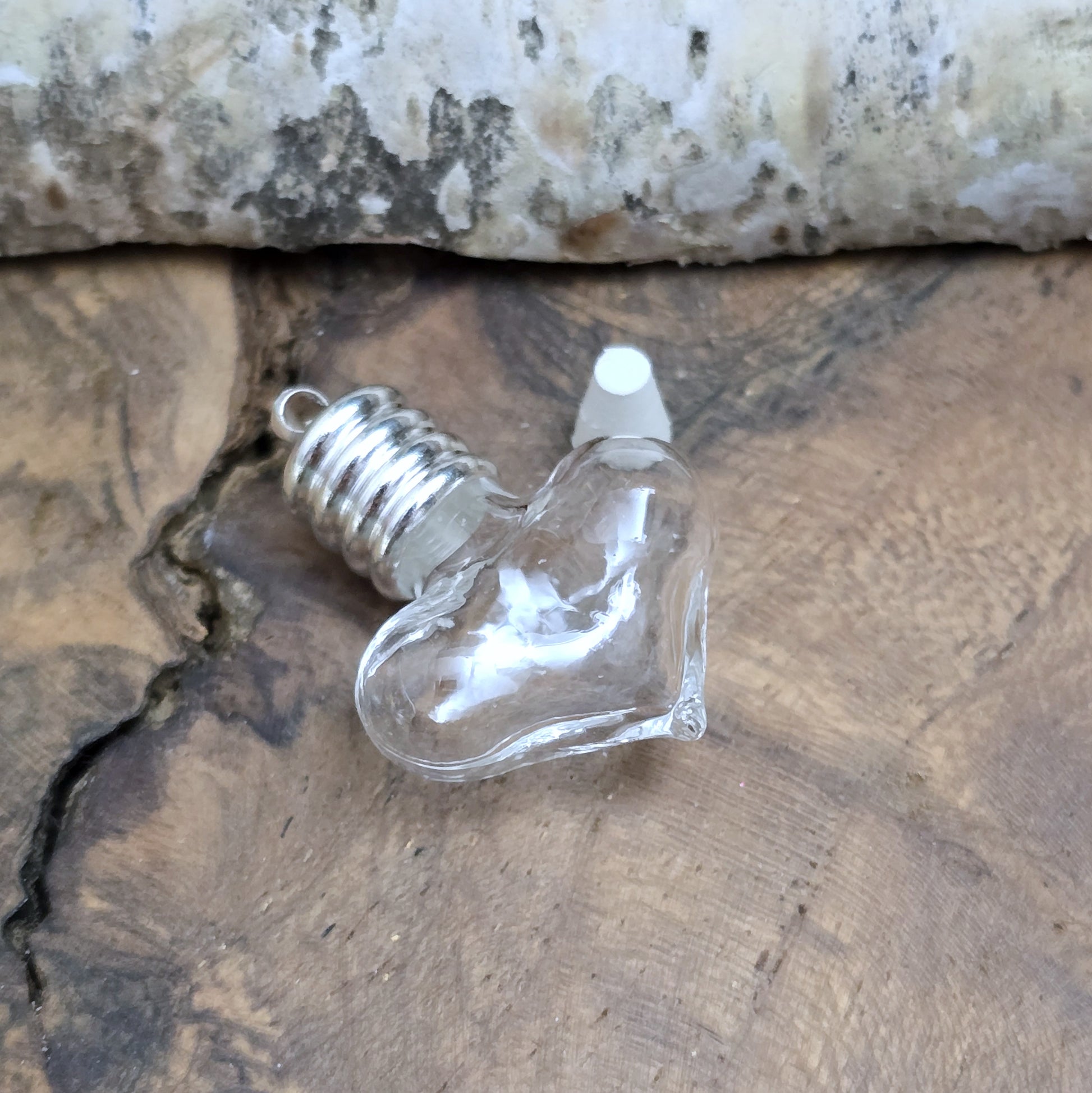 Kleiner Phiolenanhänger aus Glas, in Form eines Herzens mit silberfarbiger Kappe. Ideal zum Befüllen mit beschriftetem Reiskorn, Sand, Milchzahn, Asche, Haare udg.